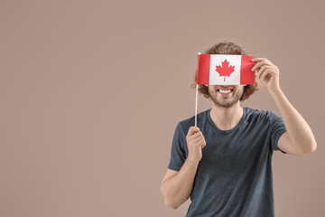 Young man with Canadian flag on color background