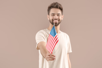 Young man with USA flag on color background