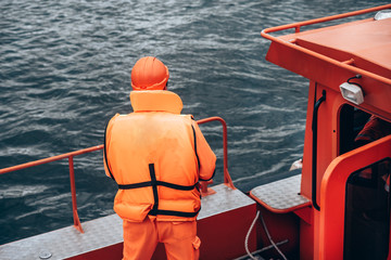 Rescue service and disaster management at sea. Lifeguard in uniform rear view on Board the rescue...