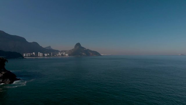 Aerial seascape view of the coast of Rio de Janeiro with the Corcovado mountain and Two Brother tops  in the background revealing a small island in the foreground