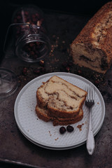Slices of homemade vanilla stirred pound cake baked in loaf pan with cinnamon sugar and hazelnut marble swirls on rustic sheet or tray with crumbs fresh from the oven on dark background
