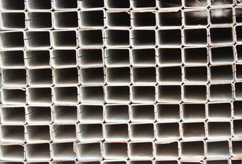 Industrial background. Pile of metal profile in a warehouse. Square metal pipe