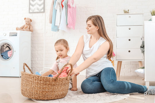 Woman and her little daughter doing laundry at home