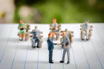 Miniature figures, business man shaking hands with group of confident business people, successful deal after great meeting.