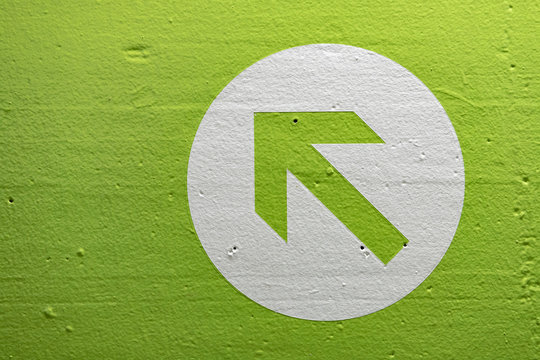 Bright Green Arrow Sign In A White Circle Pointing Up And To The Left.