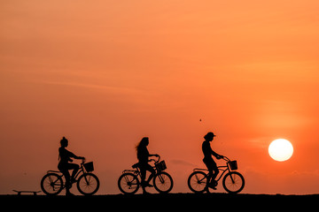 Obraz na płótnie Canvas Silhouette of people riding a bicycle in a amazing sunset in Cartagena, Colombia