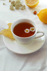 Tea with lemon and herbs. Summer or autumn still life with tea and daisies. Provence style