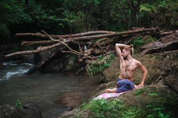Fototapeta na wymiar Yoga practice and meditation in nature. Man practicing near river