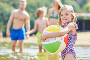 Mädchen spielt mit einem bunten Ball im Meer