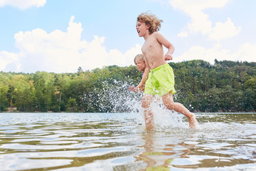 Zwei Kinder laufen und spielen im See