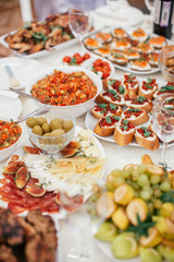 Different salad and snack and sandwitches on the white table. Stand-up meal olives, cheese, fruits.
