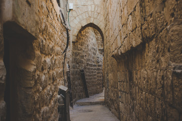 old city Jerusalem back street narrow alley with with arch passage between high stone and brick walls 
