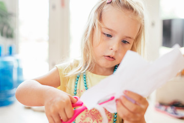 Little blonde girl with scissor at preschool. Education.Portrait of a little Cute baby girl cutting a paper.