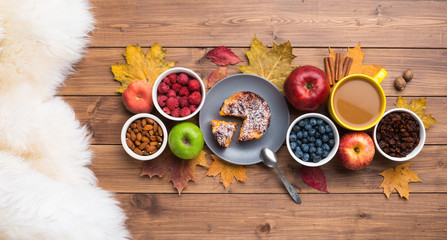 Seasonal autumn background. Frame of maple leaves and a cake over wooden background.