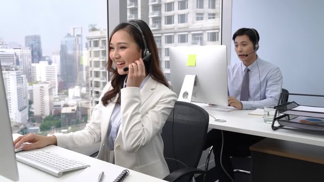 Asian customer service operator team talking on headsets and using computer at call center office in the city