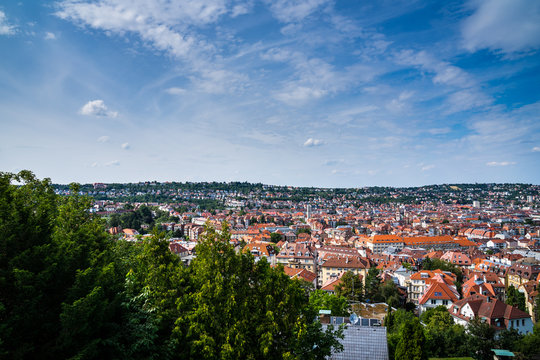 Germany, Summer sky over houses and roofs of stuttgart city in valley surrounded by trees and forest