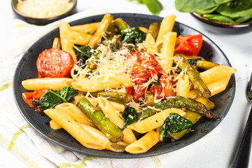 Vegan pasta penne with spinach, asparagus and tomato.