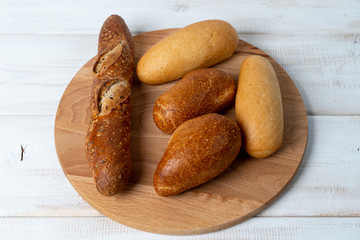 wheat, rye and multigrain baguettes on cutting board. Different bread on wooden cutting board.