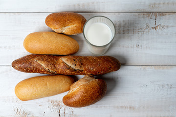 baguettes with milk on white wooden table. Rustic breakfast.