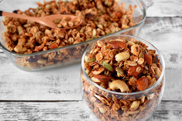 Granola with different nuts in a glass jar on the white wooden table