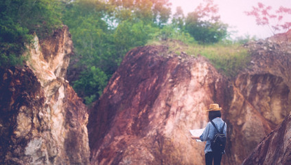 Back of solo travel in local asia, Teenager traveler holding map while hiking on mountain, Solo tourist traveller with map standing on top of stone hill background, Summer travel vacation