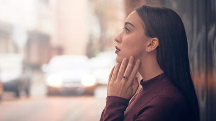 Sad young woman posing on the street.
