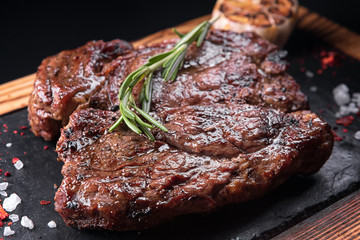 Fried meat steak on slate on a black background