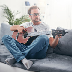 Man playing acoustic guitar in the living room.