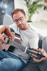 Obraz premium Man playing acoustic guitar in the living room.