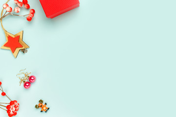 Сomposition made of red christmas decoration with christmas  star, berries, toy elk, gift box on turquoise background. Copy space for text. Flat lay, top view