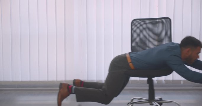 Closeup portrait of crazy attractive businessman riding on the chair happily in the office indoors on the workplace