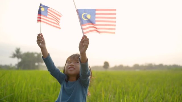 happy malaysian kid with national flag outdoor