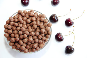 corn chocolate sweet balls in a glass plate and cherry berries on a white background