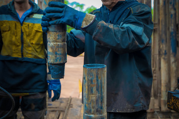 Offshore oil rig worker prepare tool and equipment for perforation oil and gas well at wellhead platform. Making up a drill pipe connection. A view for drill pipe connection from between the stands