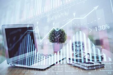 Obraz premium Stock market graph on background with desk and personal computer. Double exposure. Concept of financial analysis.