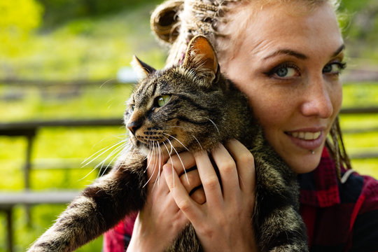 Loving young woman cuddling her cat to her cheek