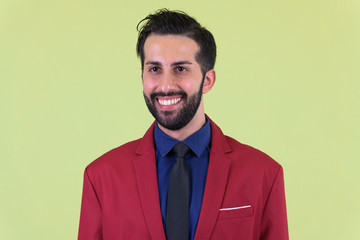 Face of young happy bearded Persian businessman in suit thinking