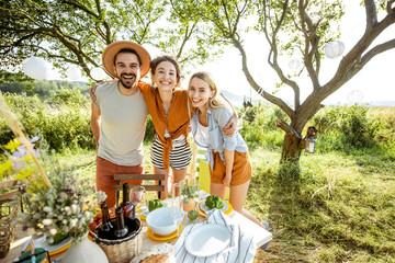 Portrait of a young happy friends hugging together in the garden or backyard during the festive...
