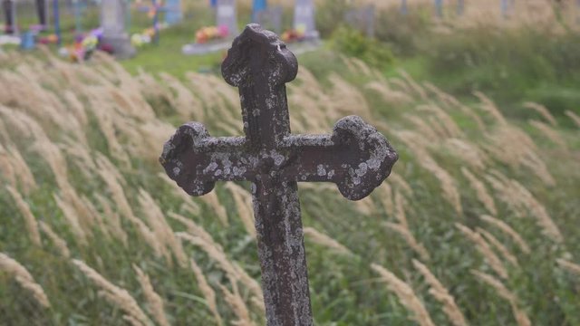 Old terrible stone cross on cemetery on background of sky