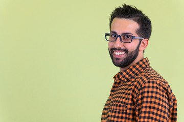 Obraz premium Closeup profile view of happy young bearded Persian hipster man looking at camera