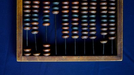 Vintage wooden abacus close up. Counting wooden knuckles. Part of the old end of the abacus on a dark blue background.