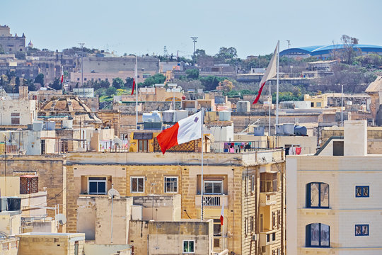 Maltese white - red flag against typical malta residential buildings.