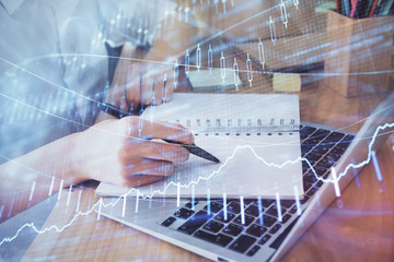 Financial charts displayed on woman's hand taking notes background. Concept of research. Double exposure