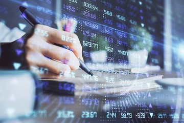 Fototapeta premium Financial forex charts displayed on woman's hand taking notes background. Concept of research. Double exposure