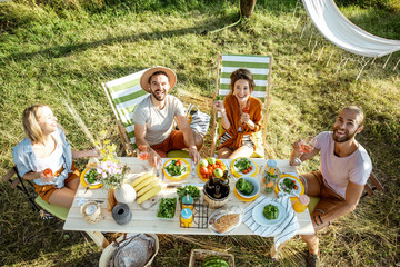 Group of a young friends having festive lunch in the beautifully decorated garden on a summer...