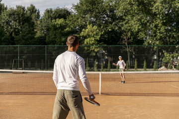 Couple playing tennis against each other