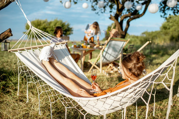 Young woman relaxing with wine glass on the hammock, during a lunch with friends in the garden on a...