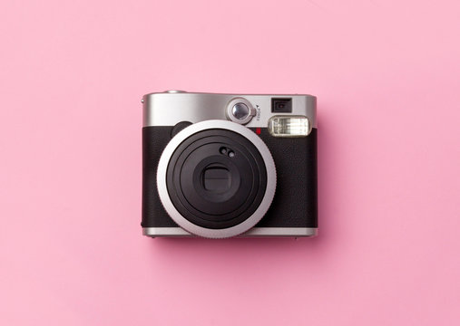 Vintage instant camera at pastel pink background.