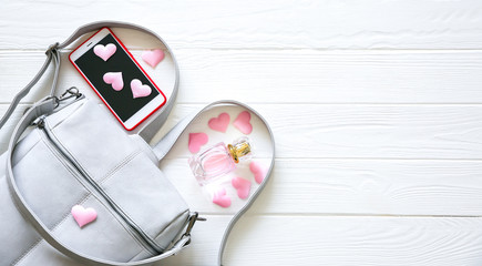 Phone, stylish bag and perfumes on white background. Beautiful flat lay with hearts. The best present for the girl. Woman's or mother's day idea.