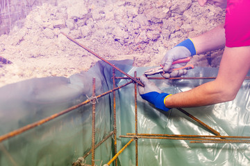 Man knitting metal rods with pillars for concrete